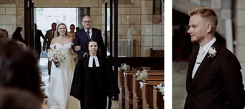 Eine Braut in weißem Kleid und Schleier schreitet bei einer Hochzeit in Hannover zum Altar. Begleitet wird sie von einem älteren Mann und einer jüngeren Frau in Priestergewändern. Rechts steht ein Mann im Anzug mit Ansteckblume. Die Kulisse ist eine elegante Kirche mit Holzbänken.